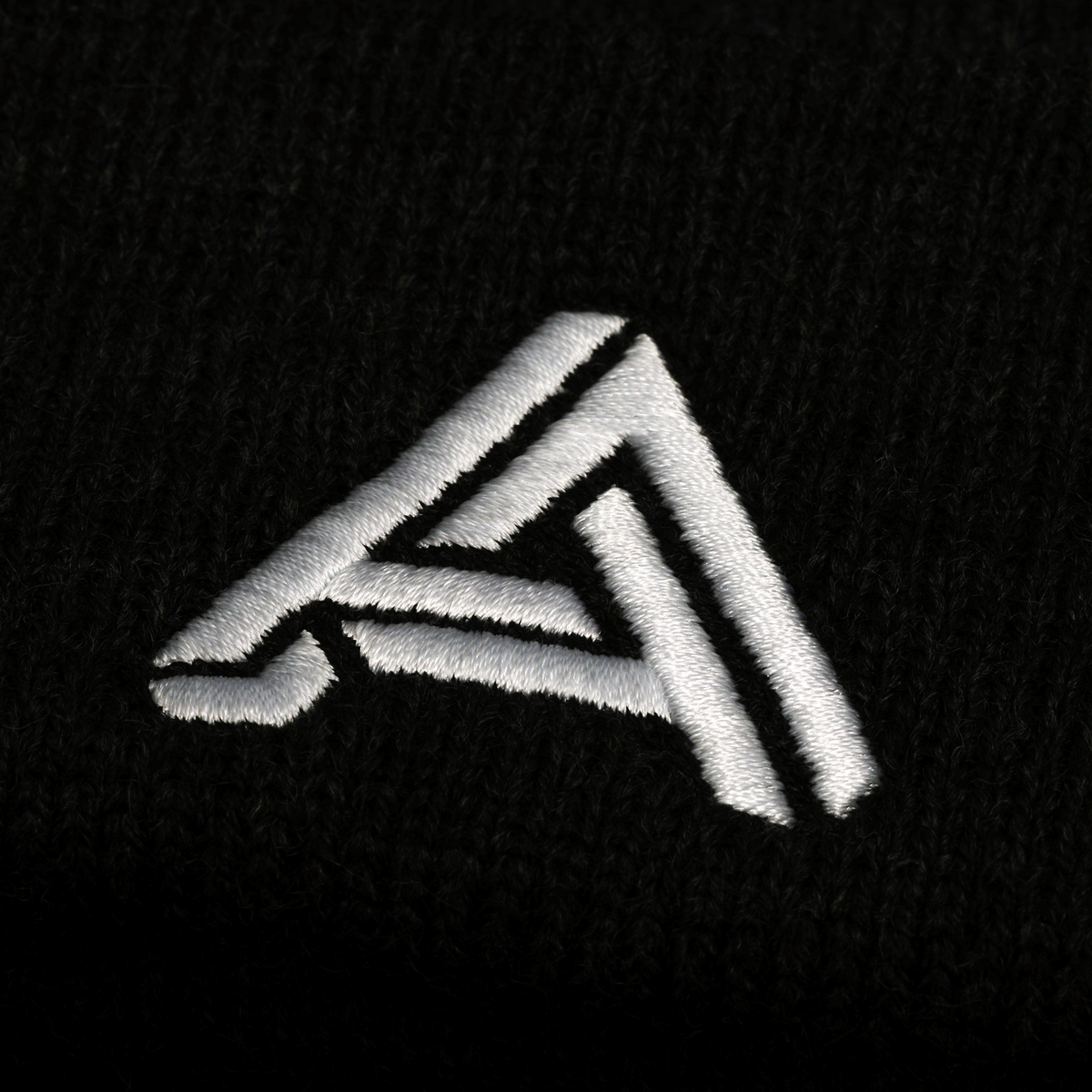 Black knitted beanie with white embroidered logo, versatile style for cold weather fashion.